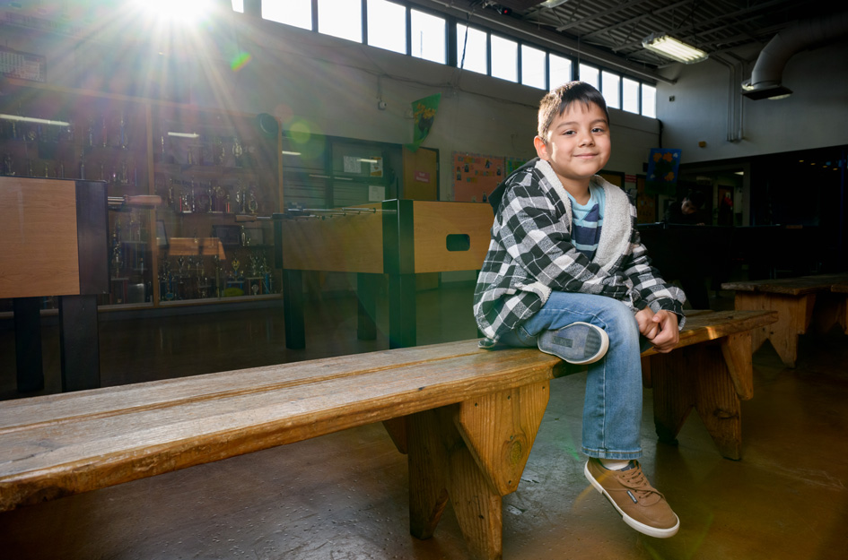 Club kid sitting on bench smiling at camera