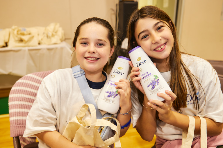 Club girls smiling at camera holding Dove product