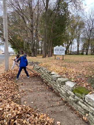 Club kids raking leaves off sidewalk