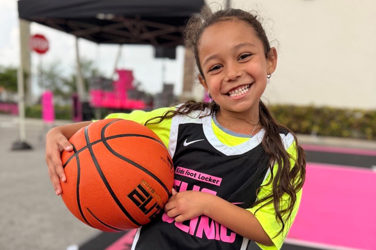Club kid with basketball smiling at camera