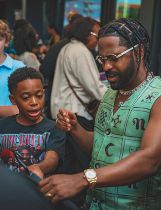 Langston H. selling one of his t-shirt designs to Big Sean. Image courtesy of Boys & Girls Clubs of Southeastern Michigan.
