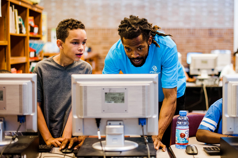 Club kid and Youth Development Professional working on computer
