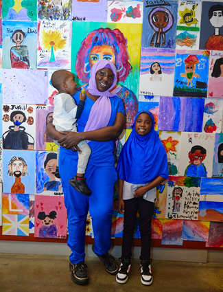 Club kid and parent in front of art In honor of Hispanic Heritage Month
