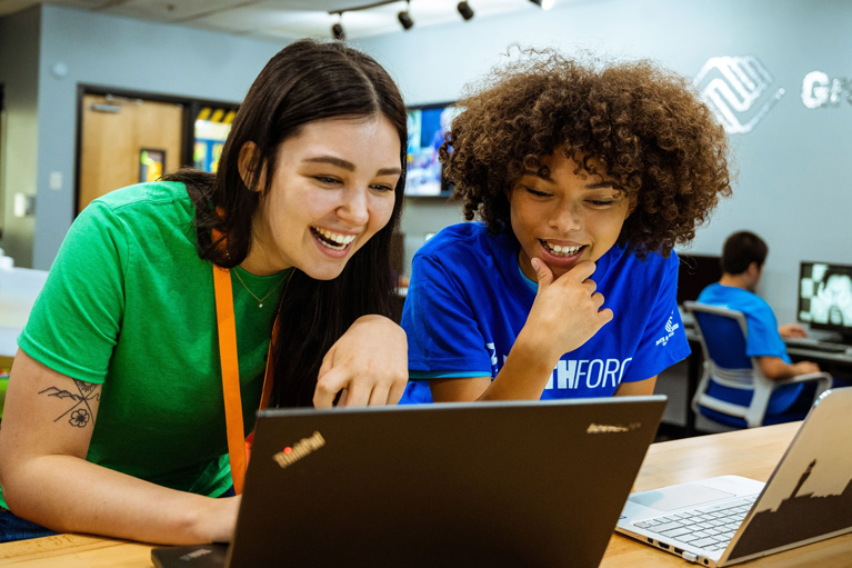 Two teens look at laptop